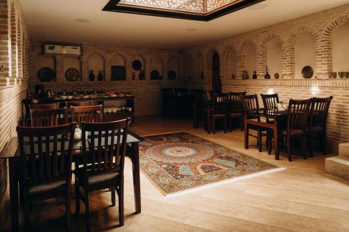un comedor con mesas, sillas y una alfombra en Hotel SHOHRUD, en Bukhara