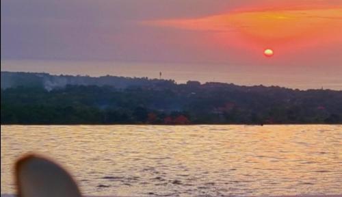a sunset over a body of water with a boat at Uluwatu Sunset Hills in Uluwatu