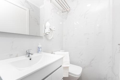 a white bathroom with a sink and a toilet at Príncipe Apartamentos e Suites in Lisbon