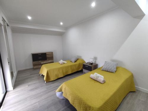 アルマカオ・デ・ペラにある8-2 Torre Sol - Casas & Papéisの黄色いシーツが備わる客室内のベッド2台