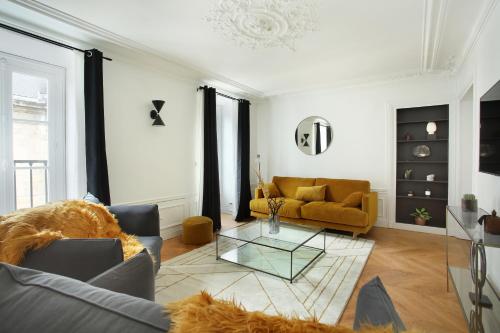 un salon avec un canapé et une table en verre dans l'établissement Residense Louvre Museum by Studio prestige, à Paris