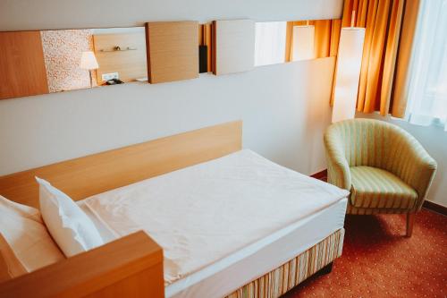 a hotel room with a bed and a chair at Hotel Brücklwirt in Niklasdorf