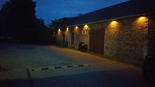 a person sitting next to a brick building at night at Appartement Vermietung Brunner in Rostock