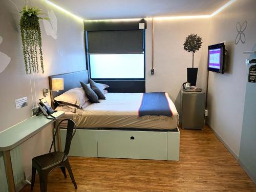 a bedroom with a bed with a desk and a window at Bannister Hotel in Johannesburg