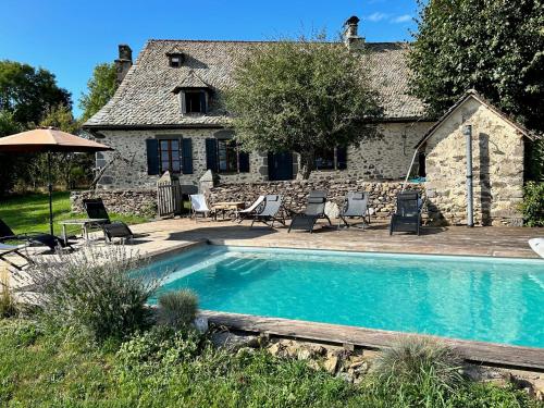 einen Pool vor einem Steinhaus in der Unterkunft Maison typique Auvergnate, piscine et four à pain in Saint-Christophe-les-Gorges