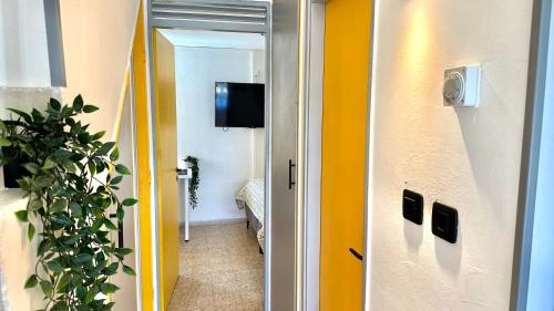 a hallway with yellow walls and a door with a television at GW317 Gugel Waves Amazing Seaview Pool Apartments in Nahariyya