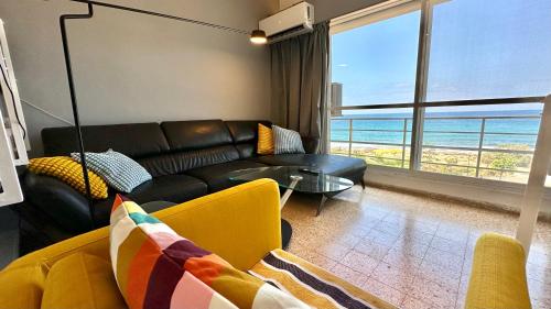 Sala de estar con sofá de cuero negro y vistas al océano en GW317 Gugel Waves Amazing Seaview Pool Apartments en Nahariyya