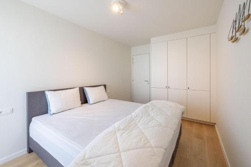 a bedroom with a large white bed and white cabinets at VivaVela in Nieuwpoort