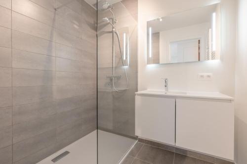 a white bathroom with a sink and a shower at VivaVela in Nieuwpoort