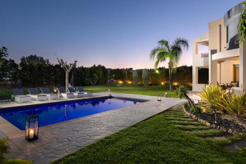 un patio trasero con piscina y una casa en Villa Rapha Maris, en Afantou