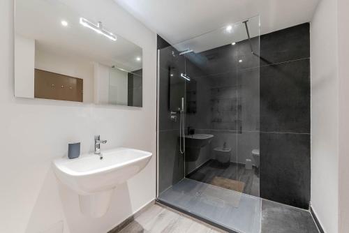 y baño blanco con lavabo y ducha. en Esclusivo bilocale centralissimo en St. Moritz