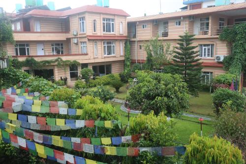 a garden in front of a building with colorful flags at Hotel Bedrock in Pokhara