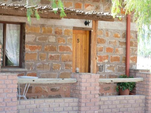 a brick house with a wooden door and a window at Duwisib Guest Farm in Duwisib