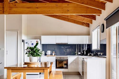 a kitchen with white cabinets and a wooden table at Prom Beach House in Sandy Point