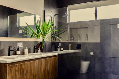 a bathroom with three sinks and a potted plant at Wamoon Retreat Apartment Luxury Gateway to Wilsons Prom in Yanakie