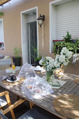 una mesa de madera con comida y flores en un patio en Chambre d'hôtes Les Magnolias, en Pontpierre