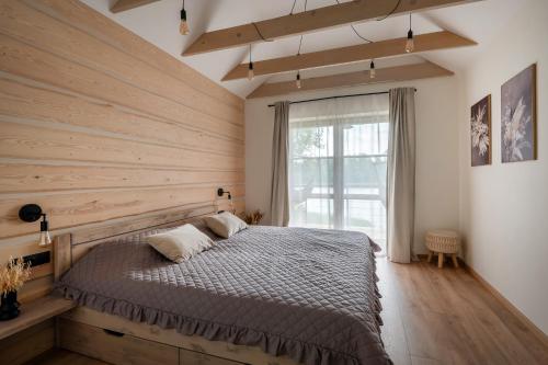 1 dormitorio con 1 cama y pared de madera en Ezermaja Akmeni, en Mordanga