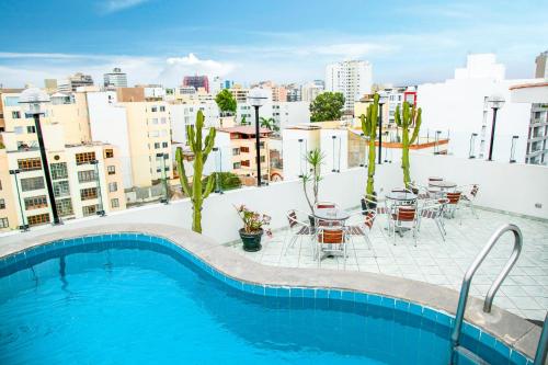 una piscina en la azotea de un edificio con mesas y sillas en Embajadores Hotel, en Lima