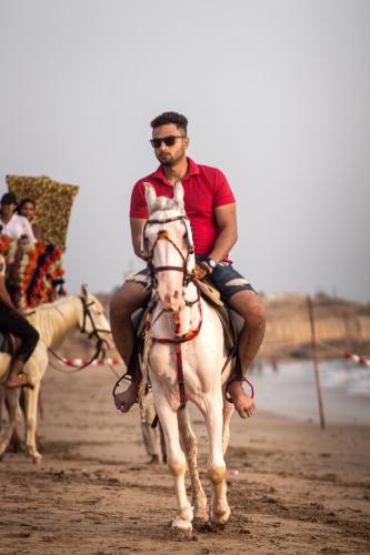 a man riding a white horse on a beach at Destination Beach Hotel by Dreamworld in Karachi