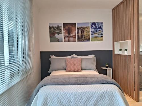 a bedroom with a bed with pictures on the wall at Lindo studio equipado em apartamento clube com academia e conforto no centro de Curitiba - MID Home in Curitiba
