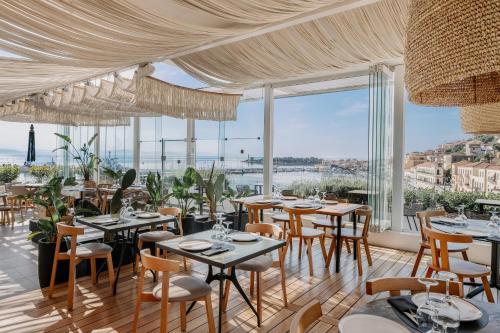 a restaurant with tables and chairs and large windows at LAS HOTEL & SPA in Gythio