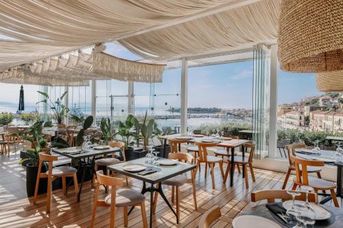 een restaurant met tafels en stoelen en grote ramen bij LAS HOTEL & SPA in Gythio