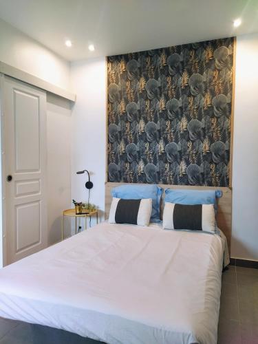 - une chambre avec un grand lit blanc et du papier peint dans l'établissement Appart-Hôtel Le Djurdjura Suresnes-Nanterre-La defense, à Nanterre