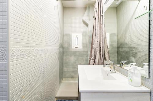 y baño blanco con lavabo y ducha. en Beachside Bliss Charming 1-bedroom, Barceloneta, en Barcelona