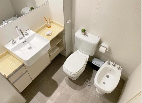 a white bathroom with a toilet and a sink at Cálidos departamentos en Ciudad con cochera in Mendoza