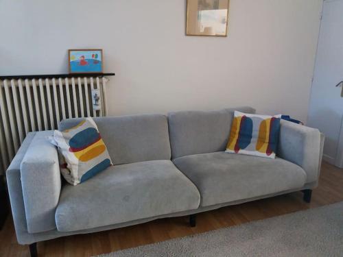 a gray couch with pillows on it in a living room at family house, free parking, 15min. walk to city in Bruges