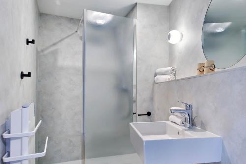 La salle de bains blanche est pourvue d'un lavabo et d'une douche. dans l'établissement Originals Boutique, Hôtel Larivaut, Puy-Guillaume, à Puy-Guillaume