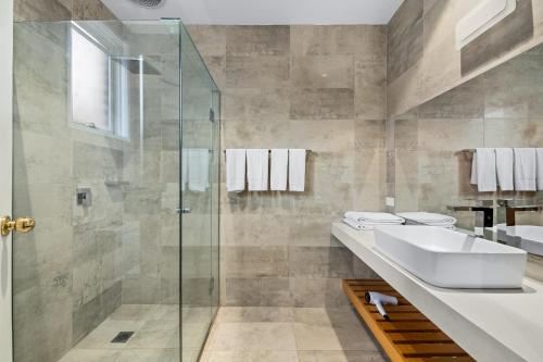 a bathroom with a sink and a glass shower at Rowville International Hotel in Rowville