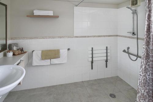 a white bathroom with a sink and a shower at Whangaparaoa Lodge in Whangaparaoa