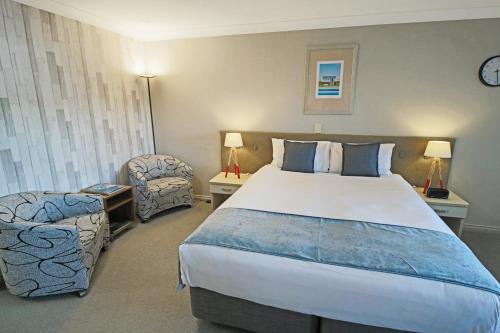 a hotel room with a large bed and a chair at Whangaparaoa Lodge in Whangaparaoa