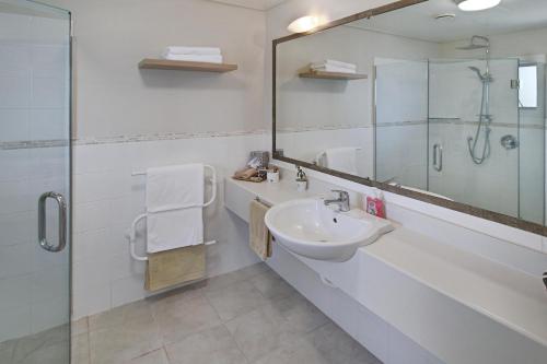 a bathroom with a sink and a shower and a mirror at Whangaparaoa Lodge in Whangaparaoa
