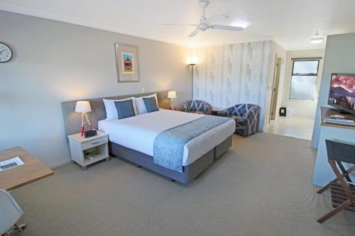 a hotel room with a bed and a chair at Whangaparaoa Lodge in Whangaparaoa