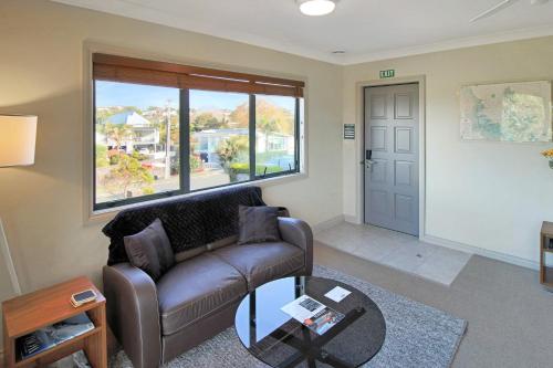 a living room with a leather couch and a window at Whangaparaoa Lodge in Whangaparaoa