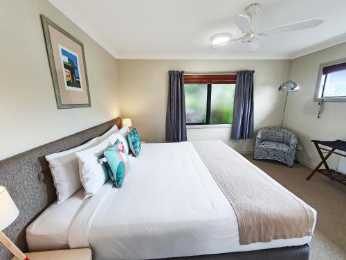 a bedroom with a large white bed with blue pillows at Whangaparaoa Lodge in Whangaparaoa