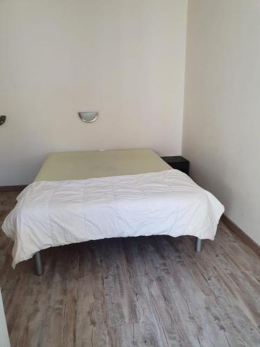 Bett in einem weißen Zimmer mit Holzboden in der Unterkunft Appartement centre de rochefort in Rochefort