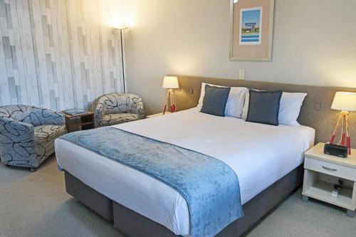 a hotel room with a large bed and a chair at Whangaparaoa Lodge in Whangaparaoa