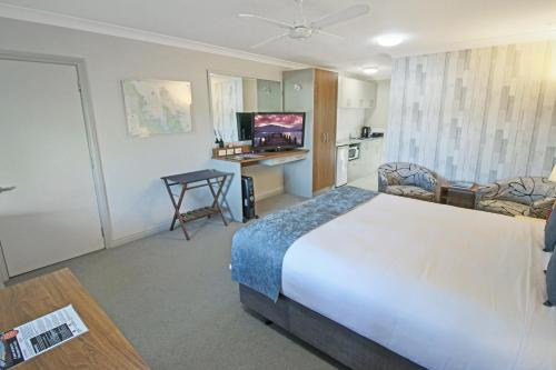 a hotel room with a large bed and a kitchen at Whangaparaoa Lodge in Whangaparaoa