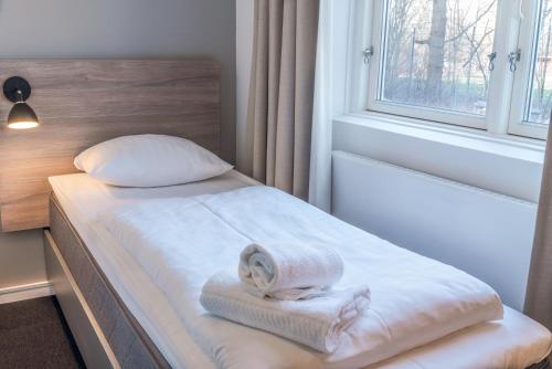 a bed with a towel on it next to a window at Copenhagen Go Hotel in Copenhagen