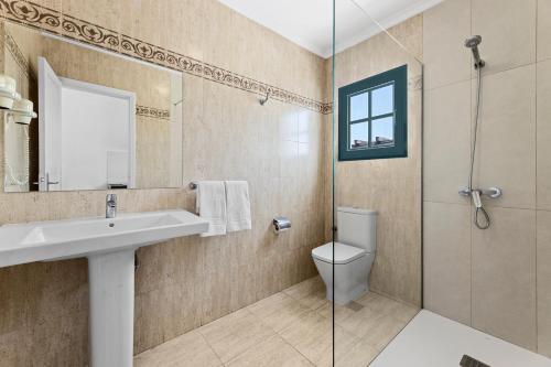 W łazience znajduje się umywalka, toaleta i prysznic. w obiekcie Apartamentos Tropicana w Puerto del Carmen