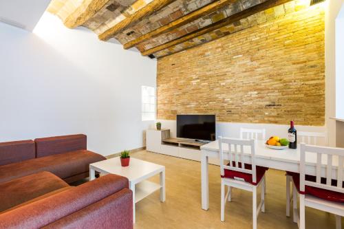 ein Wohnzimmer mit einem Sofa und einem Tisch in der Unterkunft Grcia Charm Sunlit Terrace, Ac & Exposed Brick in Barcelona