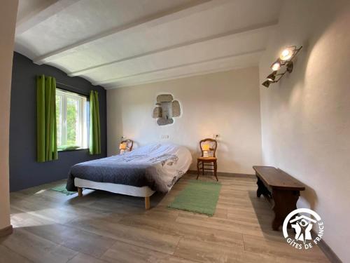 1 dormitorio con cama, mesa y cortinas verdes en MAS LO BOACH, en Saint-Laurent-de-Cerdans