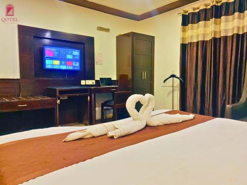 a hotel room with a bed with swans on it at Qotel Hotel Pitampura Couple Friendly in New Delhi