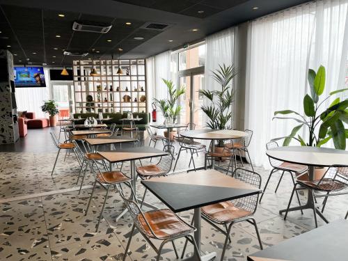 un restaurant avec des tables, des chaises et des plantes dans l'établissement ibis Martigues Centre, à Martigues