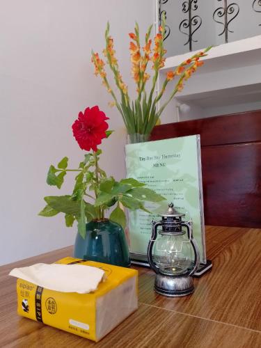 een tafel met een vaas met een bloem en een boek bij Tay Bac Sky Homestay in Sa Pa