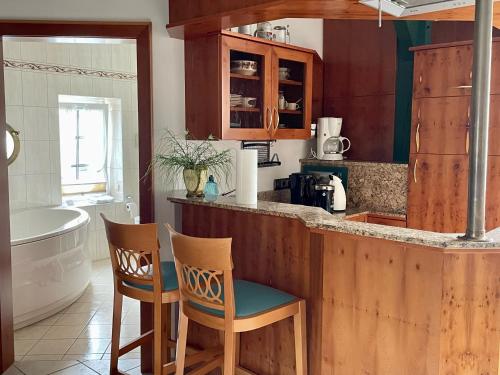 a kitchen with a counter and two chairs and a tub at Landhotel Der Buchenhof Bad Essen in Bad Essen