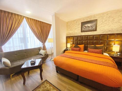 a bedroom with a large bed and a couch at Anbat Midtown Hotel in Wadi Musa
